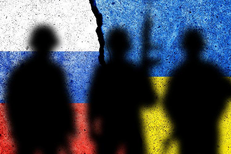The flag of Russia and Ukraine painted on a concrete wall with soldiers' shadows (© Shutterstock/Tomas Ragina) 
