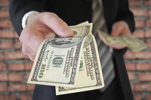 A man in a business suit offers money (copyright by Shutterstock/Oleksandrum) 