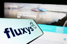 Fluxy logo on a smartphone screen infront of the website (© Shutterstock/T. Schneider)